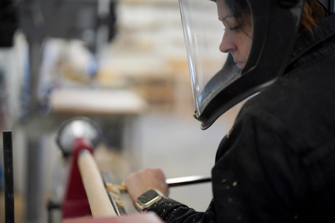 Person wearing a black hood with a clear visor in an indoor setting