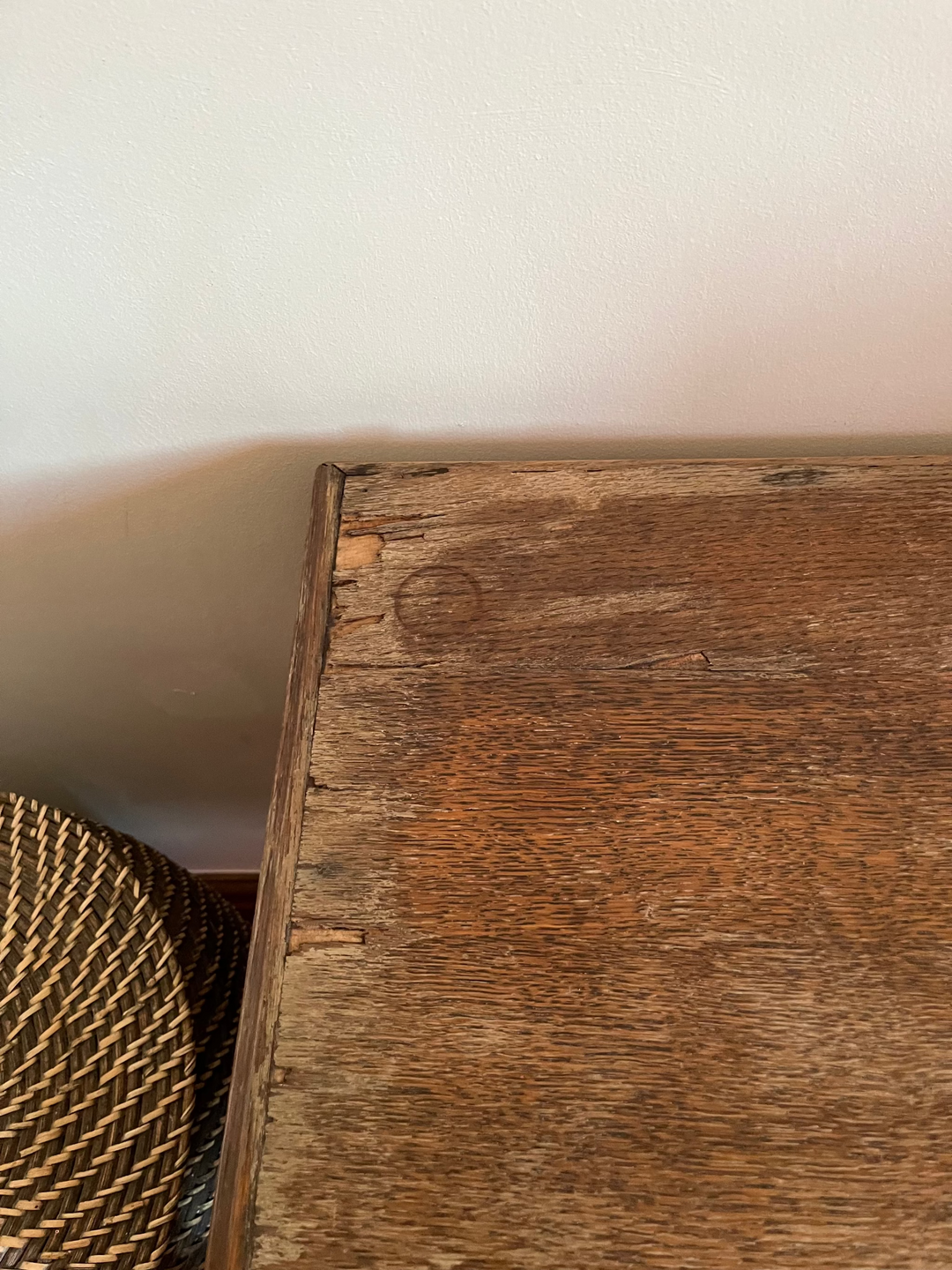 Close-up of a wooden veneered surface with wall in the background