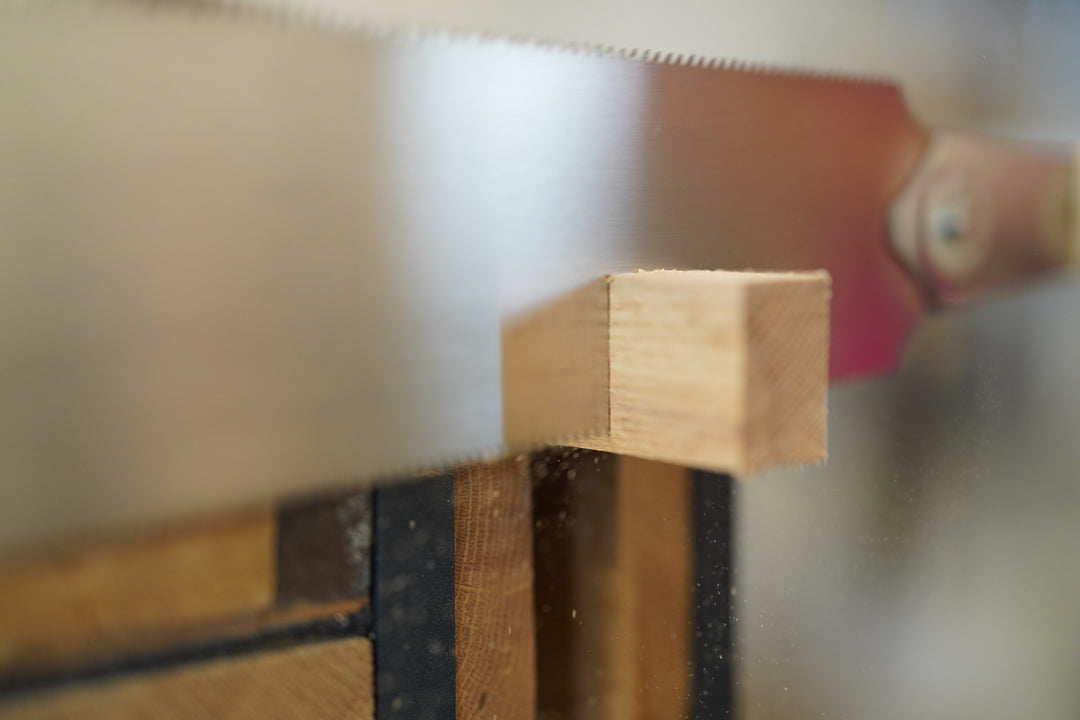 Close-up of a wooden block being cut by a saw with a blurred background