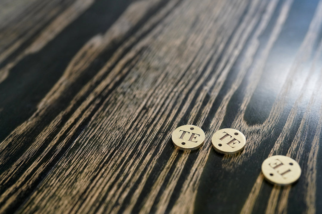 Three brass circular objects with 'TE' branding on a wooden surface